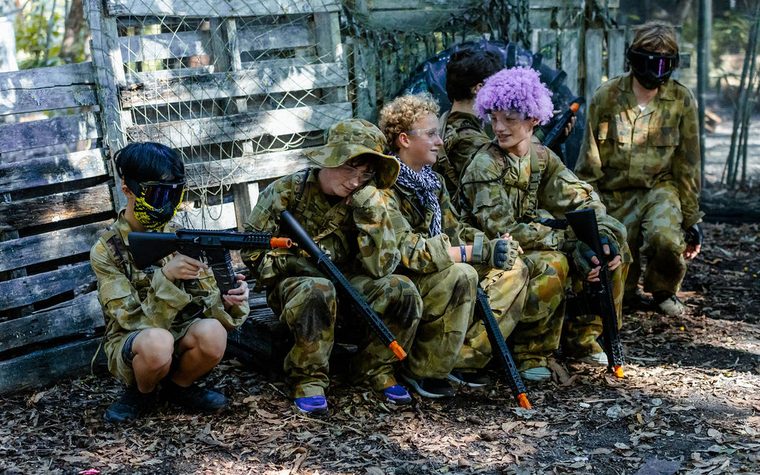 A kids' birthday group in camo between gel blasting rounds