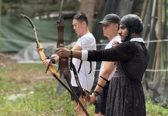 A bucks group lined up at full draw on the archery range