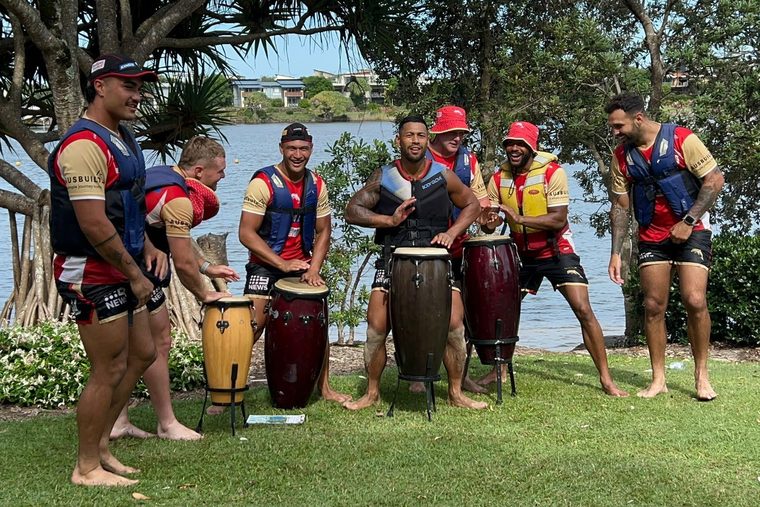 A team drumming session on the lawn by the water