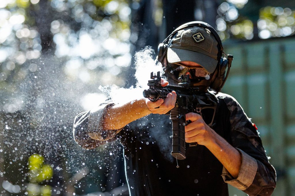 Gel balls bursting mid-air as a player fires from cover during a gel blasting game
