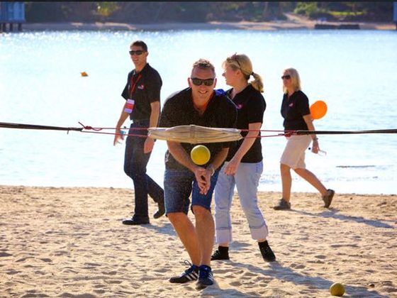 A team launching a giant catapult beside the water