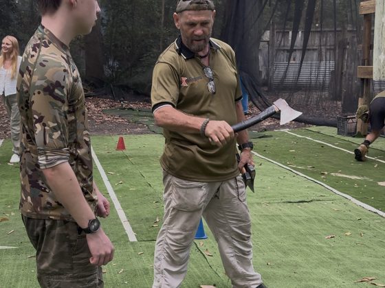 A coach teaching axe throwing technique